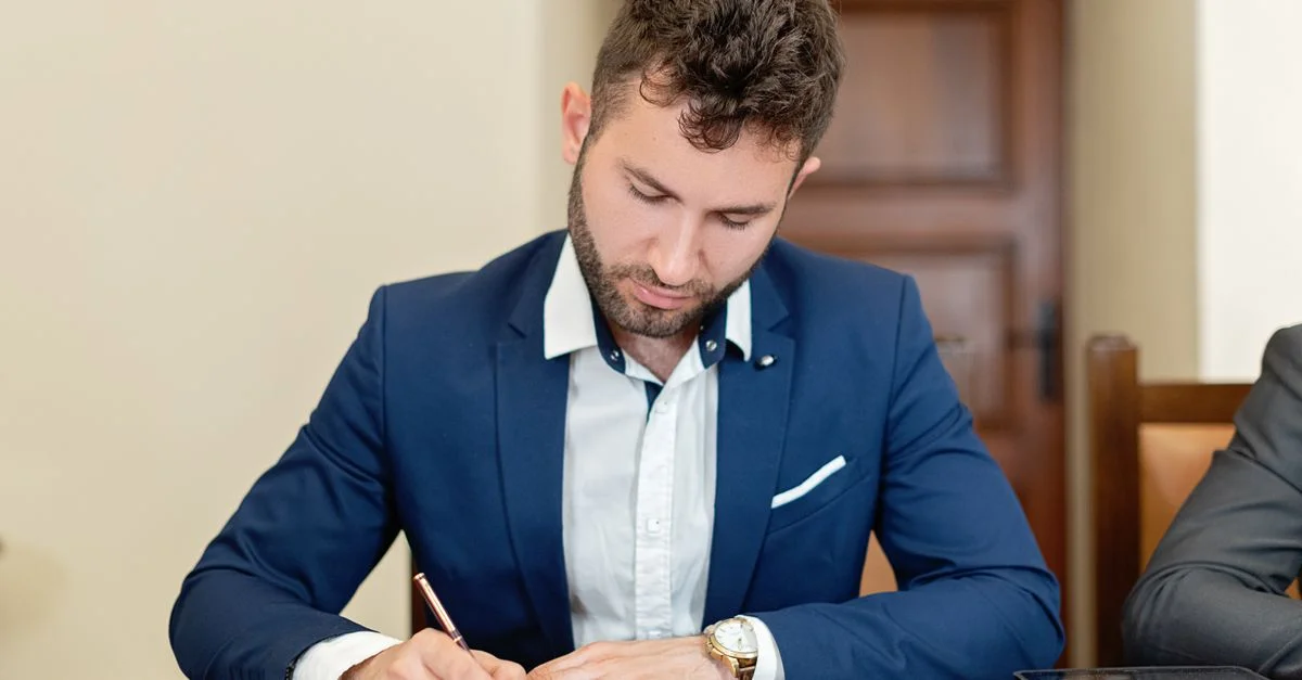 Homme d'affaires confiant en costume signant un contrat à son bureau.